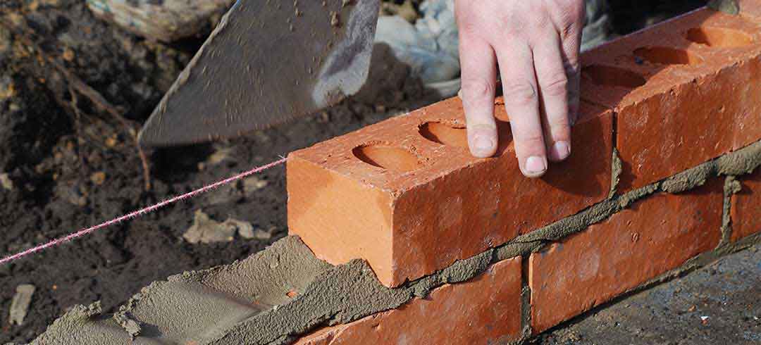Masonry Repairs - Tech laying brick with mortar