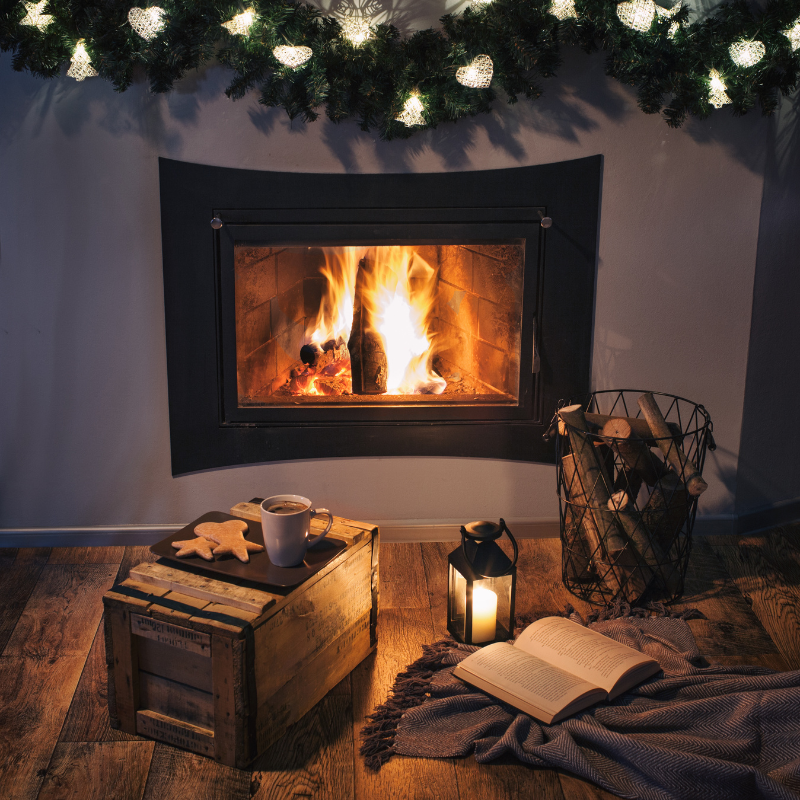 fireplace place surrounded by lights, wood pile, a book, blanket, and snacks